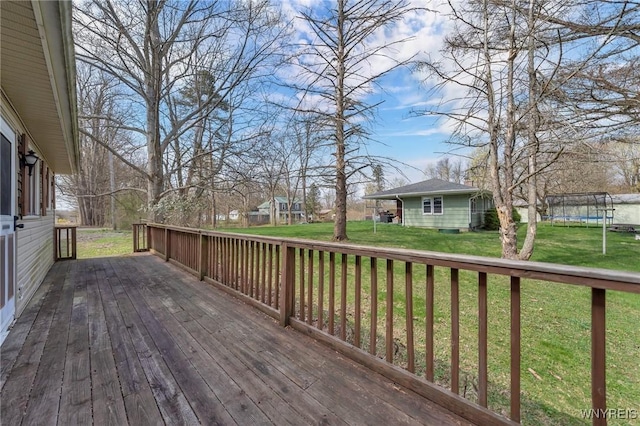 wooden terrace with a lawn, an outdoor structure, and a trampoline