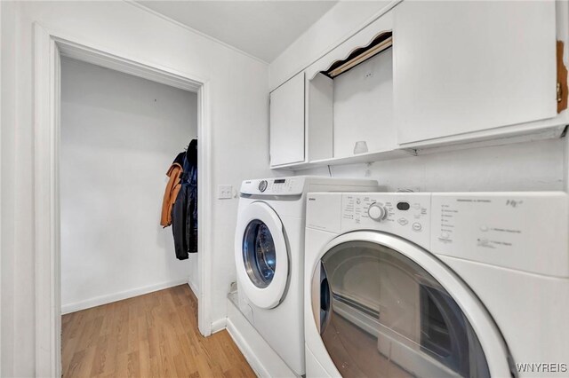 laundry area with cabinet space, light wood-style floors, washing machine and clothes dryer, and baseboards