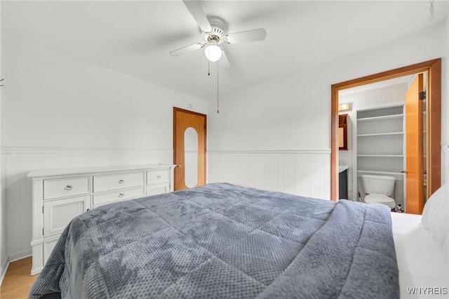 bedroom featuring wood finished floors, ceiling fan, and wainscoting