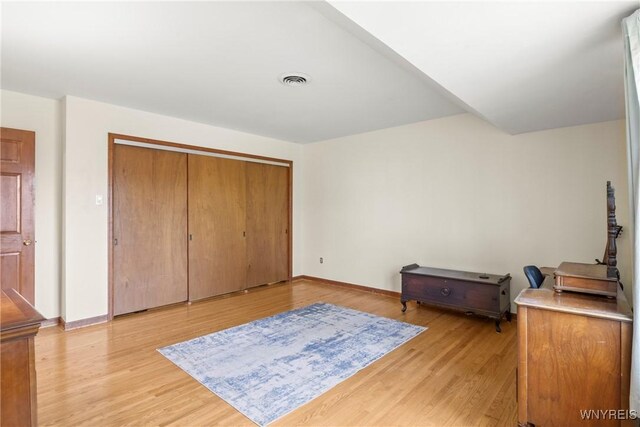 bedroom featuring light wood-type flooring, baseboards, a closet, and visible vents
