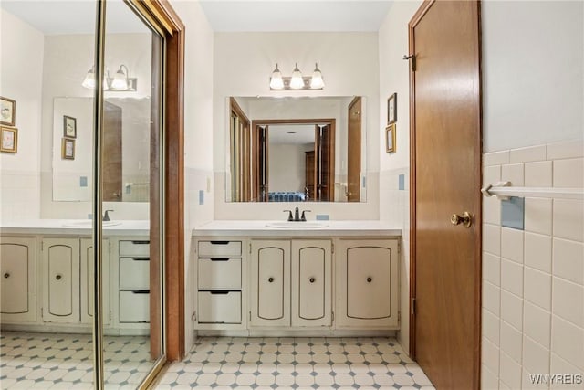 bathroom featuring tile walls, tile patterned floors, a wainscoted wall, and vanity