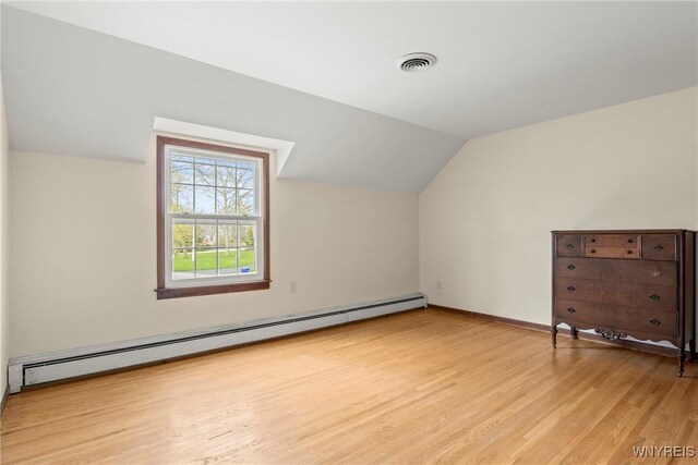 additional living space featuring light wood-type flooring, vaulted ceiling, baseboards, visible vents, and baseboard heating