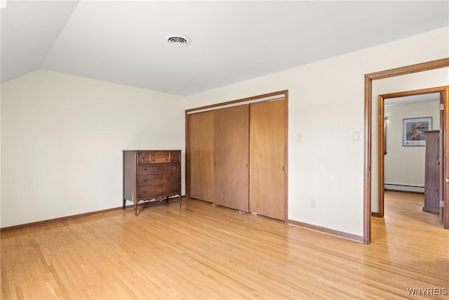 unfurnished bedroom with baseboards, light wood-style flooring, a closet, and baseboard heating