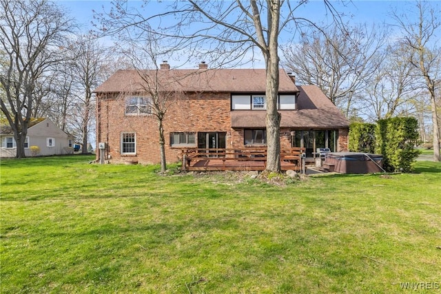 back of property with brick siding, a lawn, a hot tub, and a wooden deck
