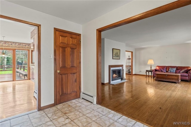 entrance foyer with a fireplace with flush hearth, light wood-style flooring, baseboards, and a baseboard radiator
