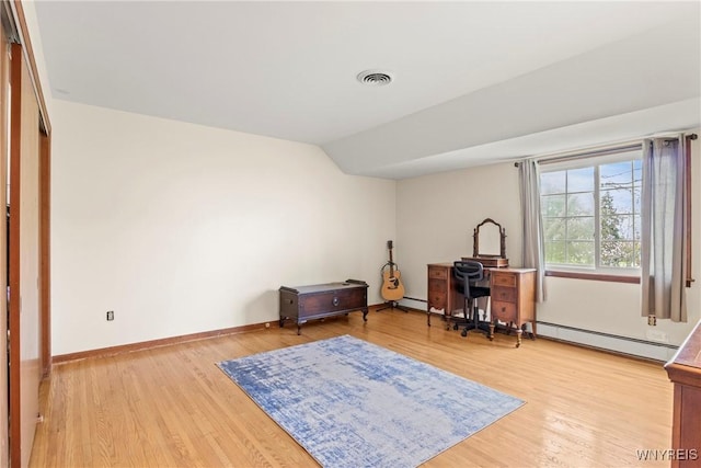 home office featuring a baseboard heating unit, vaulted ceiling, visible vents, and light wood-style floors