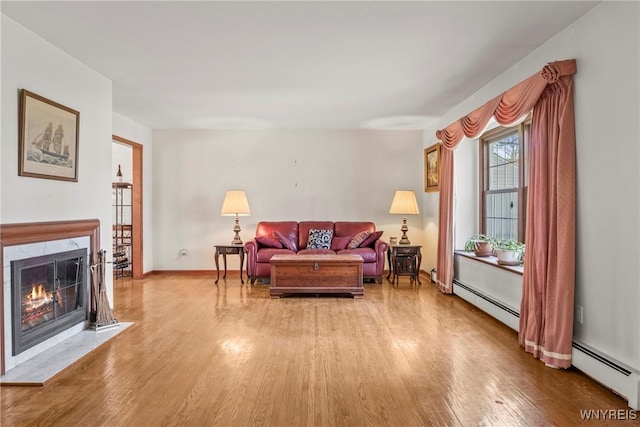 living room with a baseboard radiator, wood finished floors, and a high end fireplace