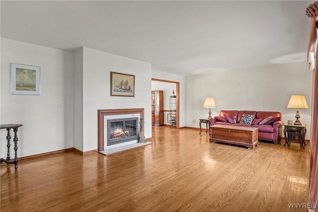 living room with a high end fireplace, wood finished floors, and baseboards