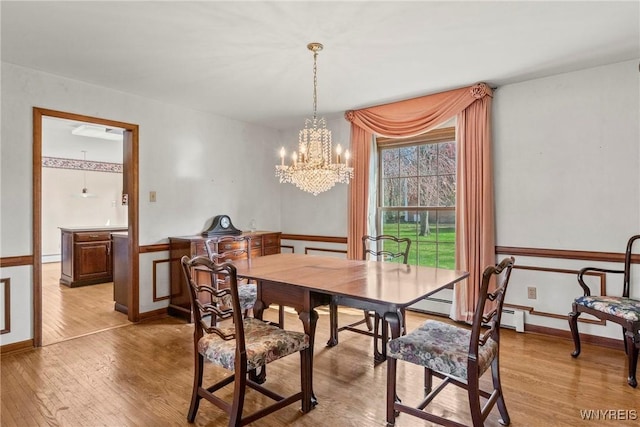 dining space with light wood-style flooring, baseboards, and a chandelier