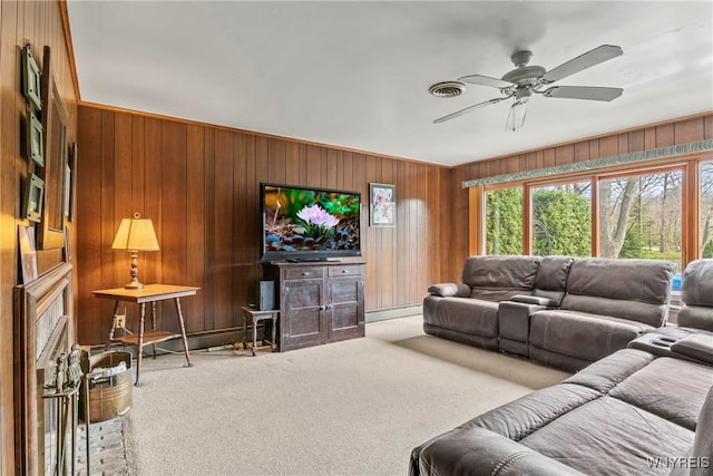 living room with plenty of natural light, a ceiling fan, wooden walls, and carpet