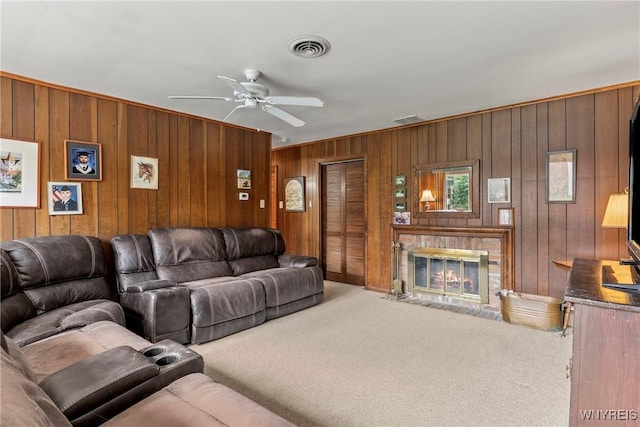 carpeted living area featuring wooden walls, visible vents, and a ceiling fan