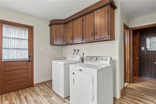 washroom with washer and dryer, baseboards, cabinet space, and light wood-style flooring
