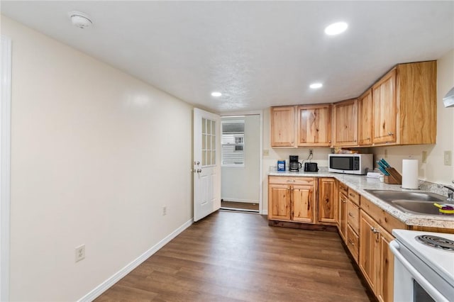 kitchen with a sink, white appliances, light countertops, dark wood finished floors, and baseboards