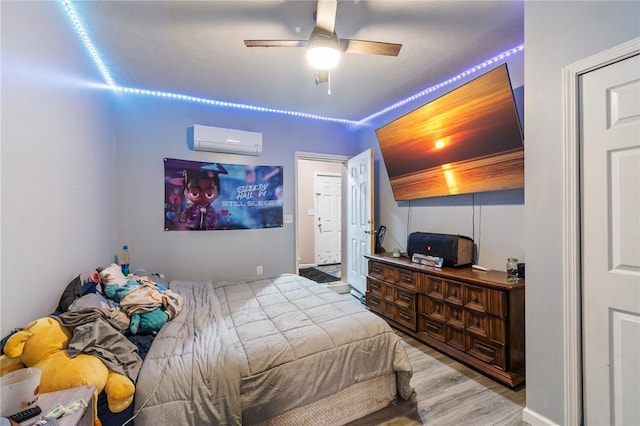 bedroom with wood finished floors, a wall mounted AC, and ceiling fan
