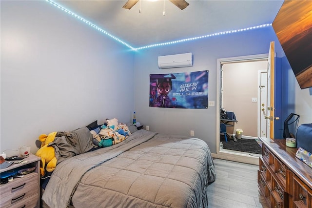 bedroom featuring wood finished floors, a wall unit AC, and ceiling fan