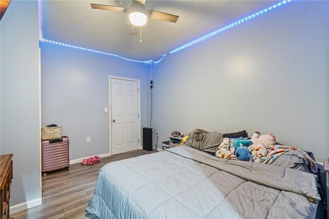 bedroom with wood finished floors, a ceiling fan, and baseboards