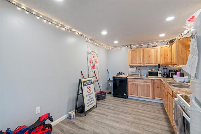 kitchen featuring recessed lighting, light countertops, a sink, white appliances, and light wood-style floors