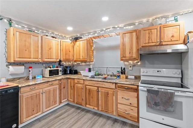 kitchen with under cabinet range hood, light countertops, a sink, white appliances, and light wood-type flooring