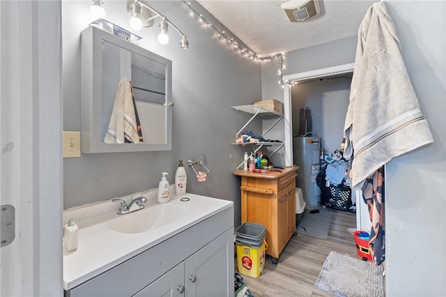 bathroom featuring visible vents, electric water heater, wood finished floors, and vanity