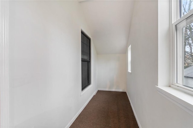 hall featuring dark colored carpet and baseboards