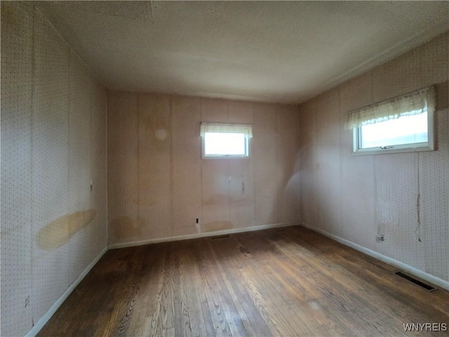 spare room with baseboards, visible vents, and hardwood / wood-style flooring