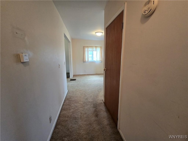 hall with carpet, visible vents, and baseboards