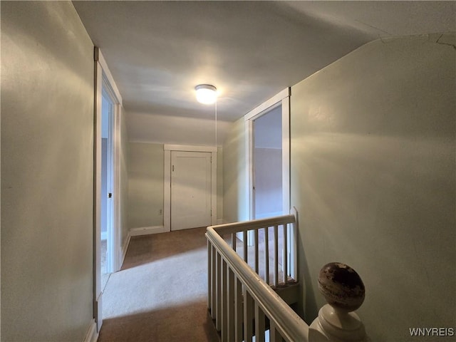 corridor with baseboards, carpet flooring, and an upstairs landing
