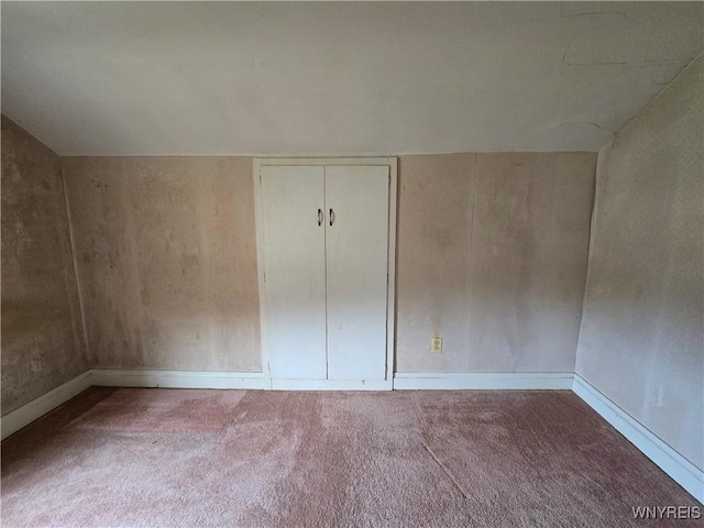 carpeted empty room with lofted ceiling and baseboards