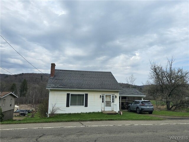 cape cod home featuring a front lawn, roof with shingles, and a chimney