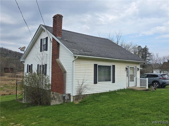 view of property exterior featuring a yard, a shingled roof, and a chimney