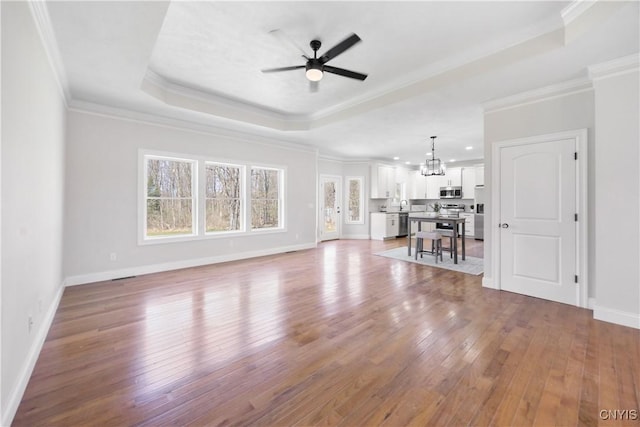 7717 Roberts St, Lenox, NY 13032 - unfurnished living room featuring ceiling fan with notable chandelier, ornamental molding, hardwood / wood-style floors, and a raised ceiling