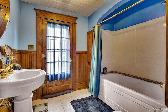 bathroom with wooden walls, shower / tub combo, tile patterned floors, and wainscoting