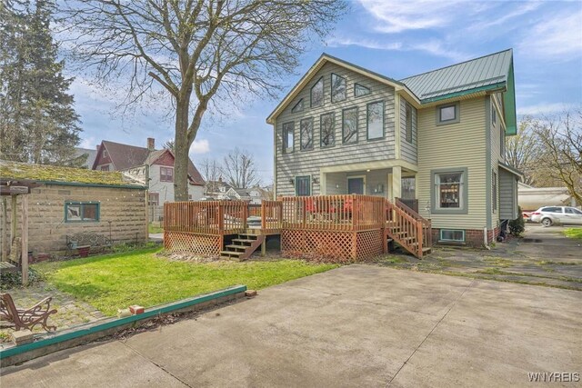 back of house featuring a lawn, stairway, a deck, and metal roof