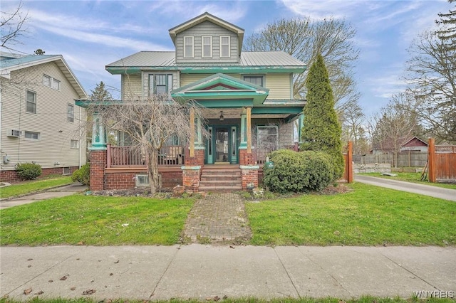 american foursquare style home with metal roof, a front lawn, covered porch, and fence