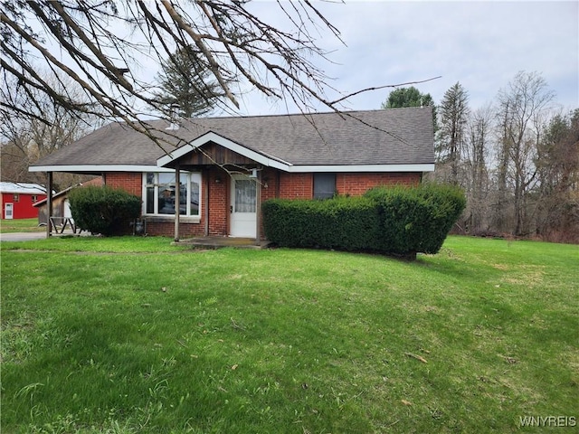 ranch-style home with brick siding, roof with shingles, and a front yard