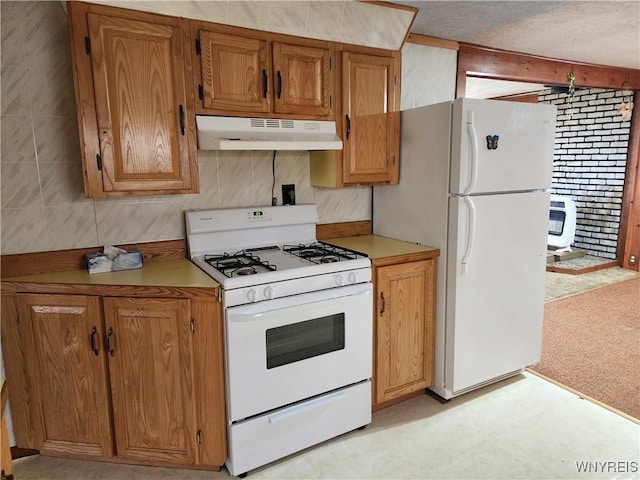 kitchen featuring brown cabinets, heating unit, under cabinet range hood, light countertops, and white appliances