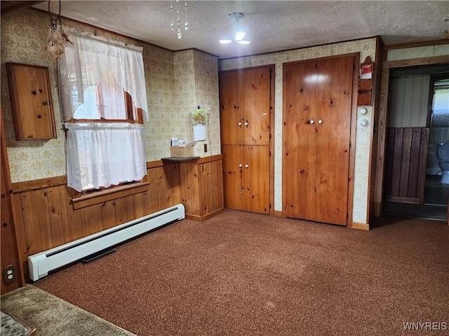 carpeted spare room featuring wainscoting, wallpapered walls, a textured ceiling, and a baseboard radiator