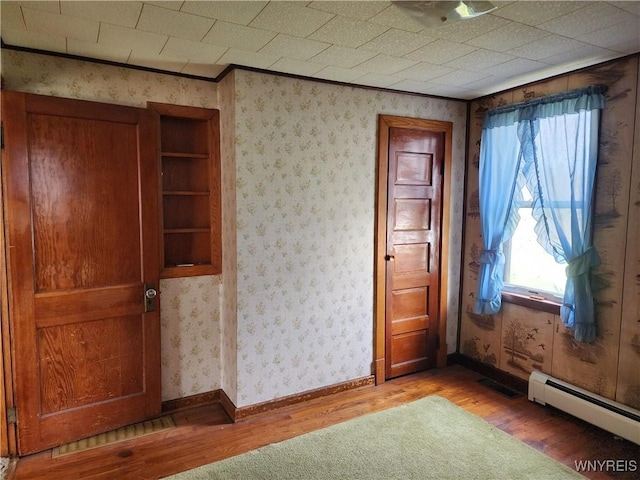 unfurnished room with a baseboard radiator, light wood-style floors, and a wealth of natural light