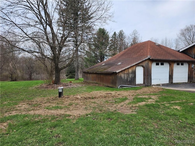 view of property exterior featuring a lawn, an outbuilding, and a garage