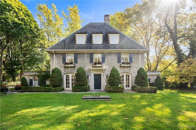 colonial home with a chimney, a front lawn, stucco siding, and french doors