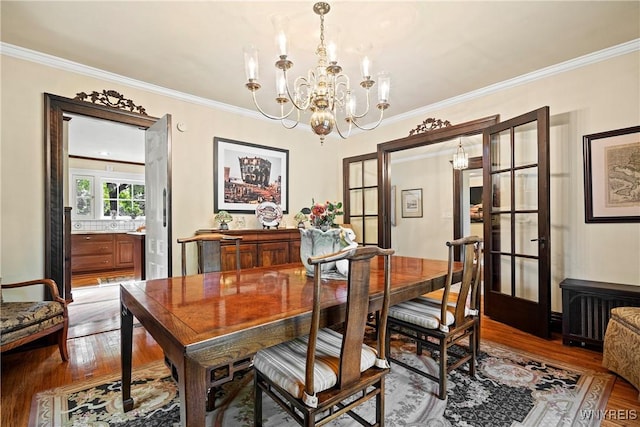 dining area featuring wood finished floors, crown molding, and an inviting chandelier