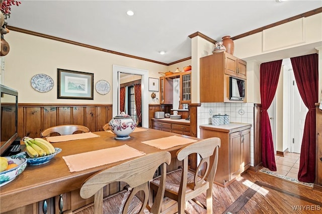 dining room featuring a wainscoted wall, recessed lighting, light wood-style floors, and ornamental molding