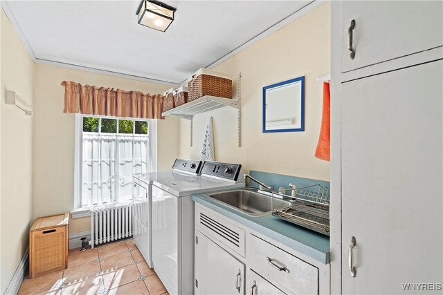 clothes washing area with a sink, radiator, independent washer and dryer, cabinet space, and light tile patterned floors