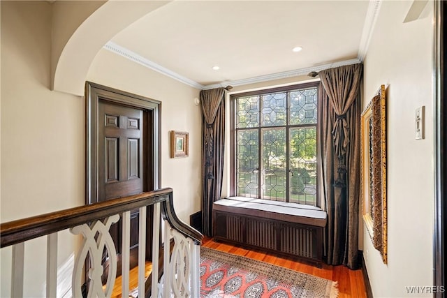 interior space with arched walkways, ornamental molding, wood finished floors, and recessed lighting