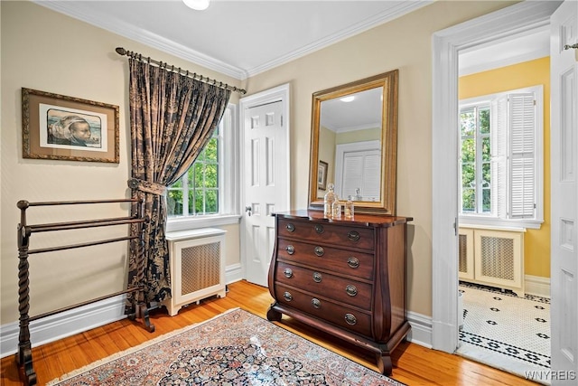 sitting room with radiator heating unit, wood finished floors, a wealth of natural light, and ornamental molding