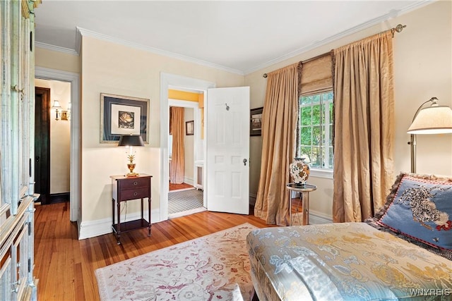 bedroom featuring baseboards, wood finished floors, and crown molding