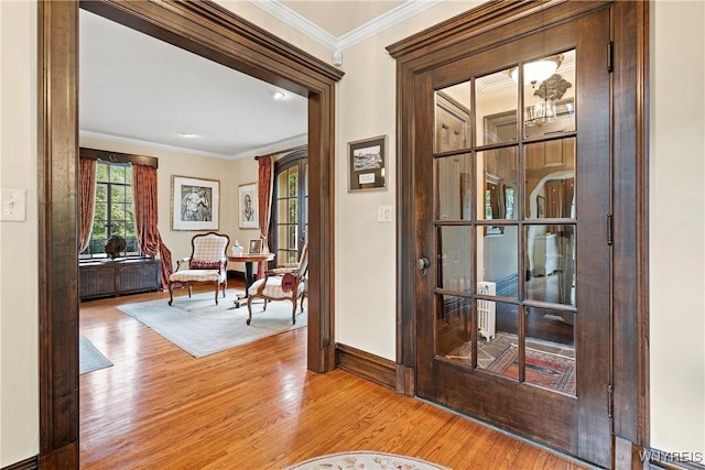 doorway with baseboards, wood finished floors, and ornamental molding