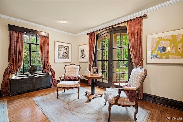 sitting room with wood finished floors, baseboards, ornamental molding, and french doors