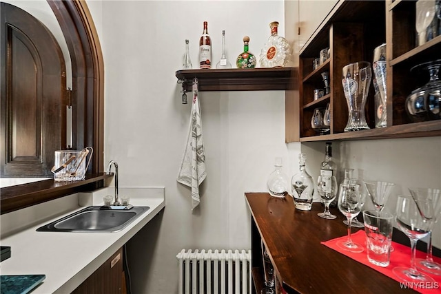 interior space with bar area, radiator heating unit, and a sink