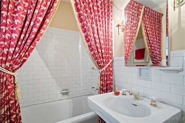 bathroom featuring wainscoting, tile walls, shower / bath combo, and a sink